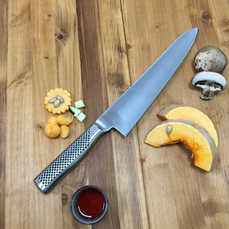 Chef profesional usando el cuchillo cebollero Global G-16 de 24 cm en cocina