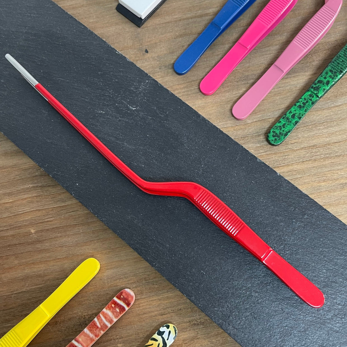 Pinza chef profesional roja con puntas dentadas para emplatado preciso